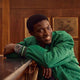 Person wearing the Waterbury Heritage Automatic GMT watch with a green jacket in a wood-paneled room.