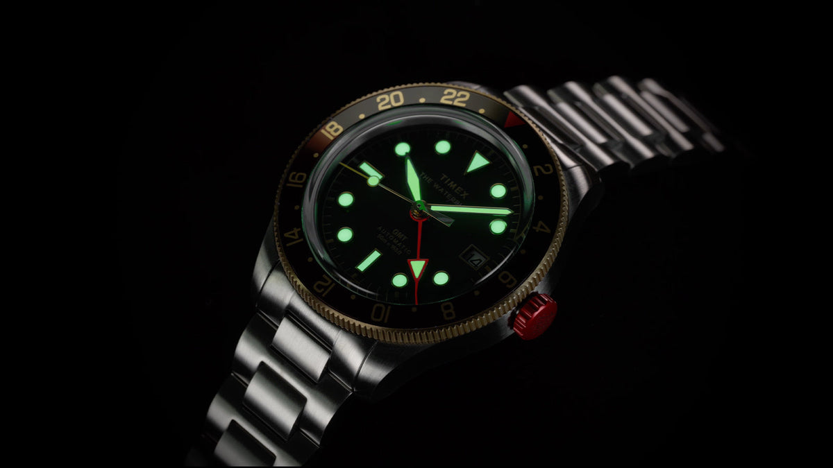 Waterbury Heritage Automatic GMT watch against a black background, showcasing its glowing hands and hour markers.