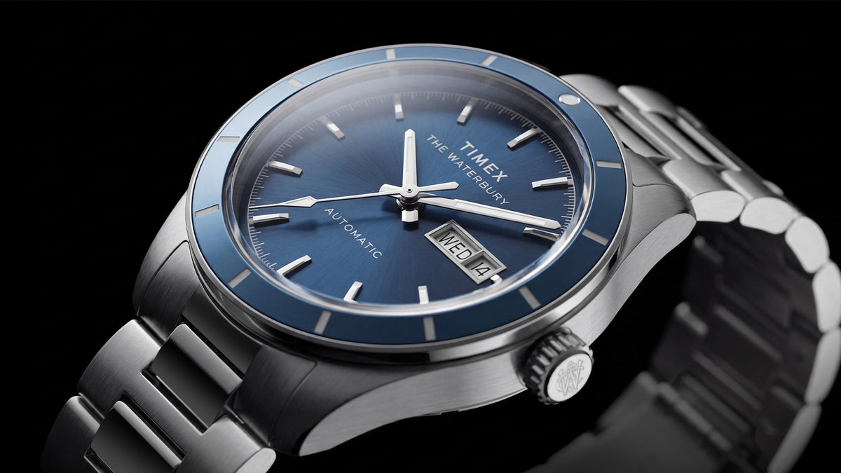 Close-up of the Waterbury Heritage Automatic featuring a blue dial, matching bezel, silver-tone markers, and day-date window.