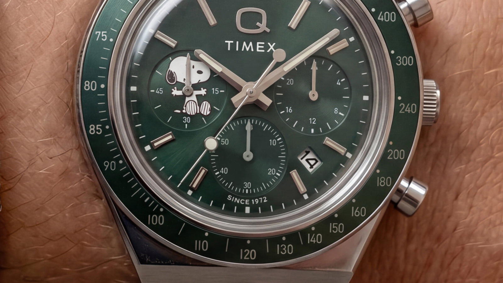 Close-up of the green chronograph dial featuring Snoopy on a subdial, silver-tone markers, and a date window.