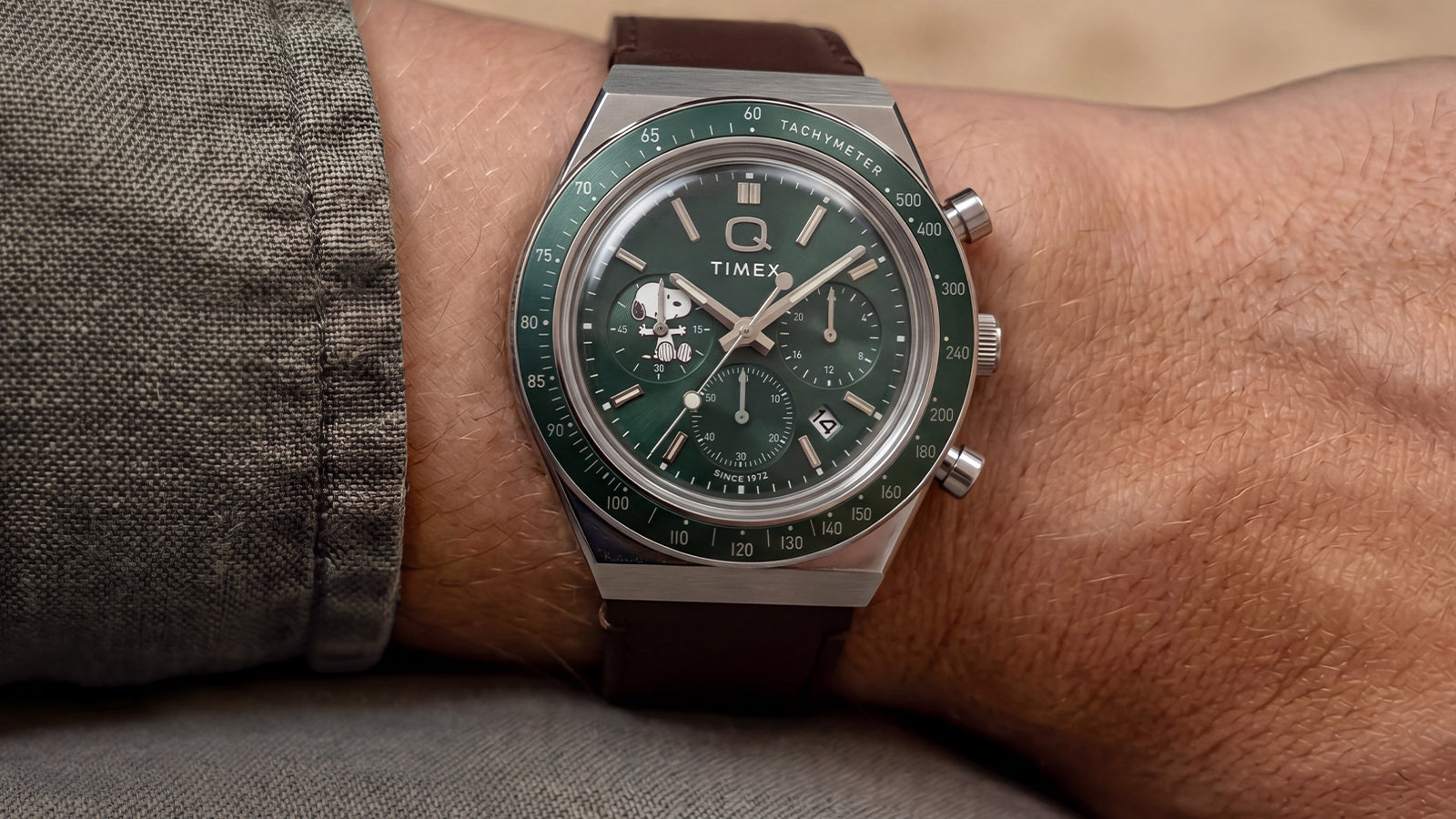 Close-up of the Peanuts® x Q Timex Chronograph with a green dial and brown leather strap worn on the wrist.