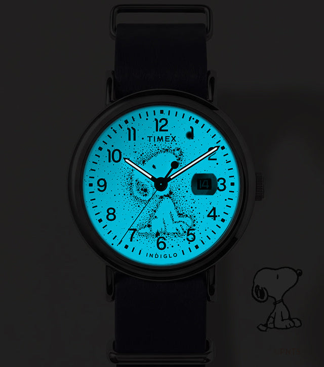 Peanuts® x Timex Weekender Astronomy watch shown in the dark with its blue INDIGLO® dial illuminating the Snoopy constellation design.