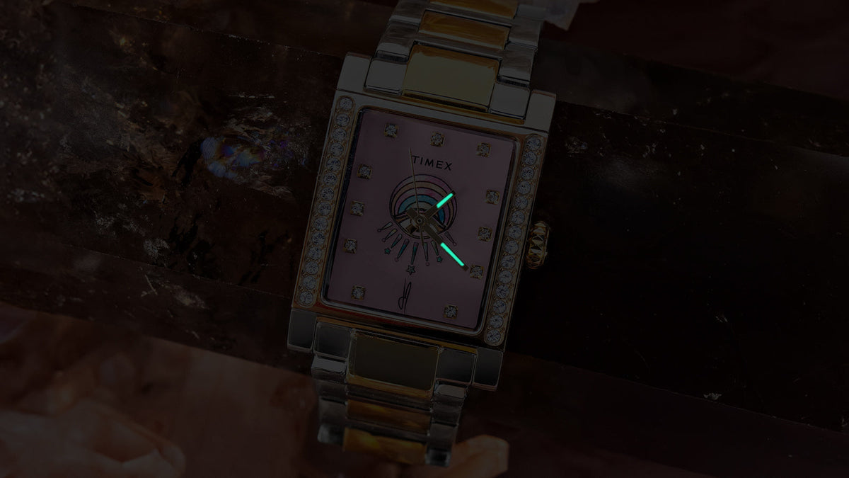 Close-up of the Timex x Jacquie Aiche Éclat watch in the dark with its hands glowing.