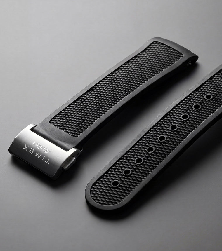 Timex Atelier NBR synthetic rubber strap in black with a textured finish and stainless-steel clasp, displayed against a dark background.