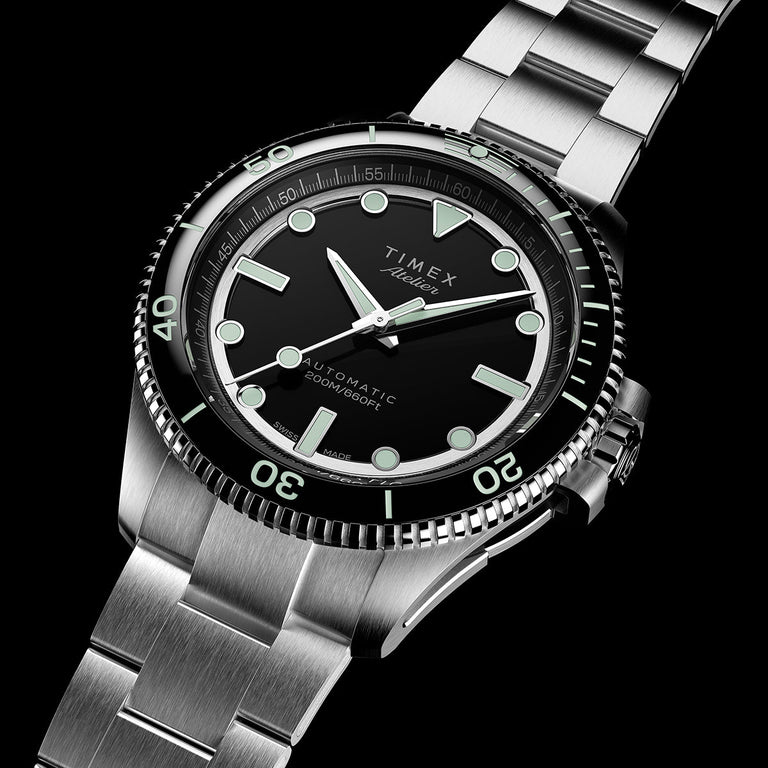 Timex Atelier automatic dive watch with a black dial, luminous markers, rotating bezel, and stainless-steel bracelet.