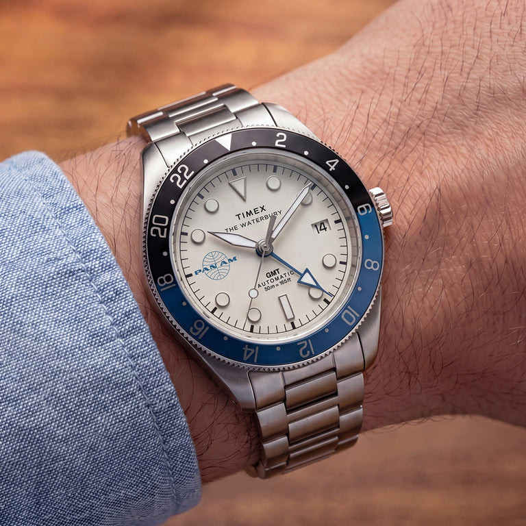 TW2Y94300 Close-up of the Pan Am x Timex Waterbury Automatic GMT watch worn with a light blue shirt.
