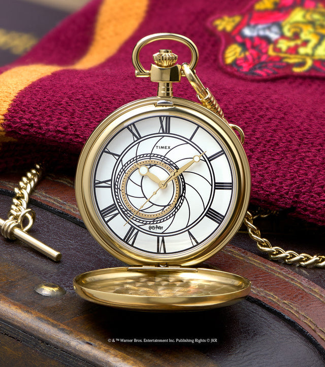 TW2Y99600 Open gold-tone pocket watch with a white Roman numeral dial and chain, displayed beside a burgundy and gold Gryffindor scarf.
