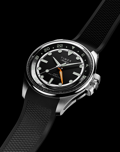 Timex Atelier GMT Automatic watch with a black dial, orange GMT hand, and black rubber strap displayed against a black background.