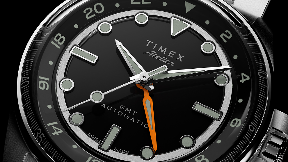 Close-up of the Timex Atelier GMT Automatic dial featuring luminous indices, polished hands, and an orange GMT hand.