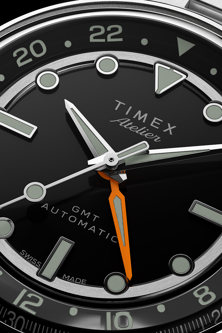 Close-up of the Timex Atelier GMT dial displaying its silver hands, orange GMT hand, and precise detailing.