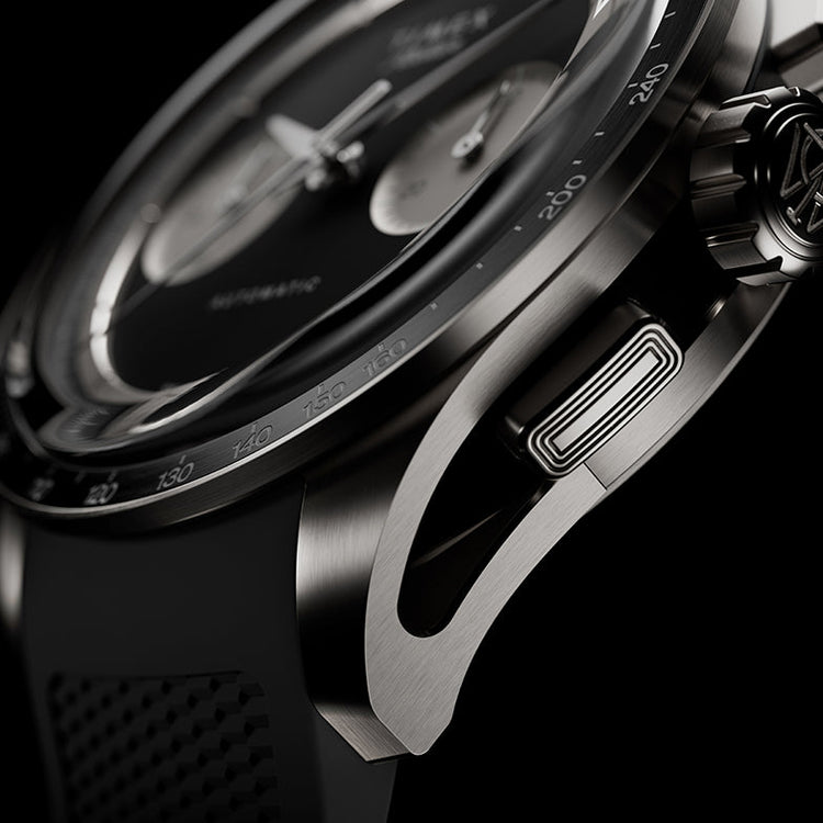 Detailed macro shot of the Timex Atelier Chronograph Automatic M1A Ti featuring a brushed titanium case, tachymeter bezel, signature crown, chronograph pusher, and precision-crafted lug design.