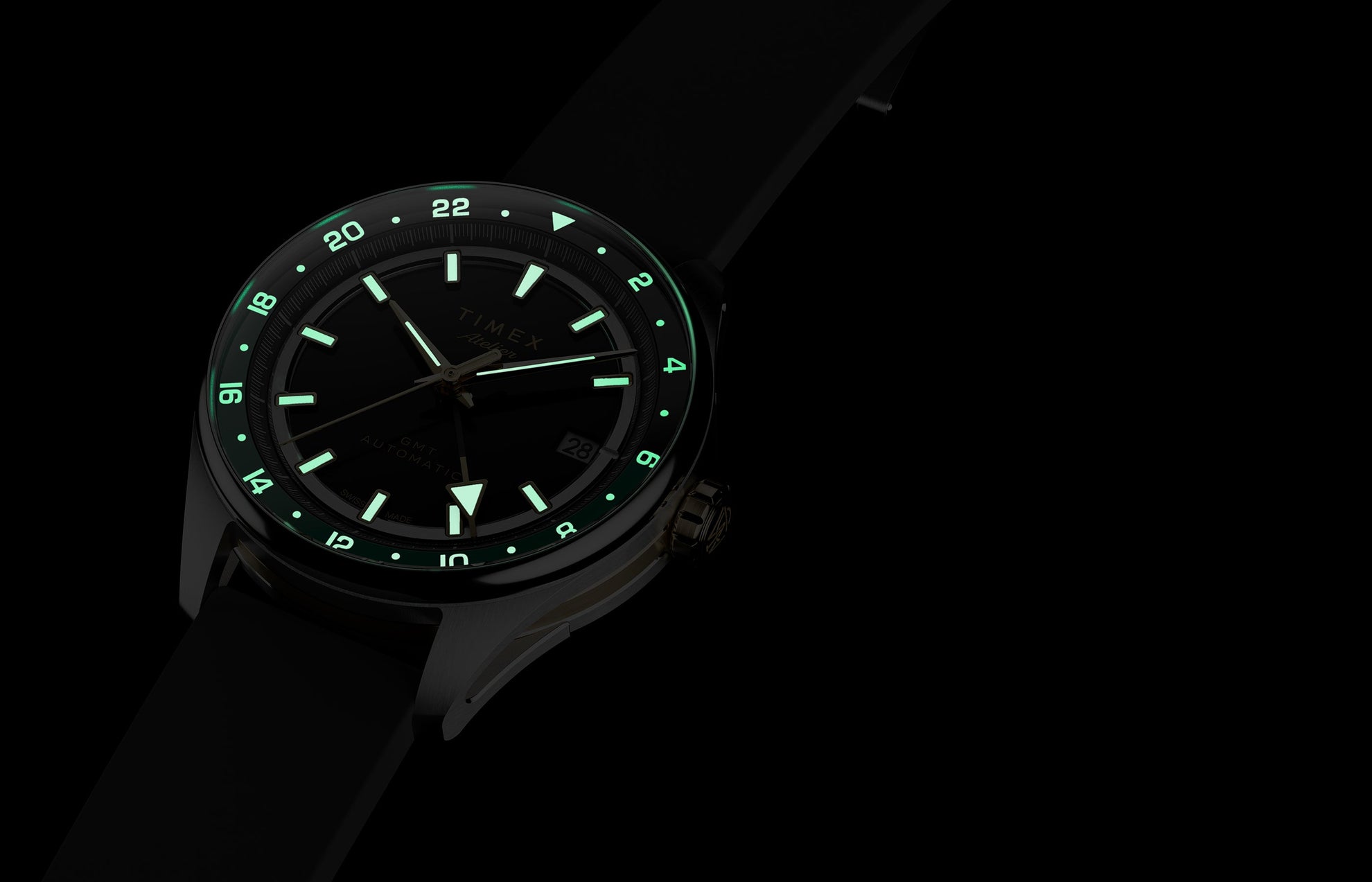 Timex Atelier GMT Première M1a watch glowing in the dark with illuminated hands, hour markers, and 24-hour scale.