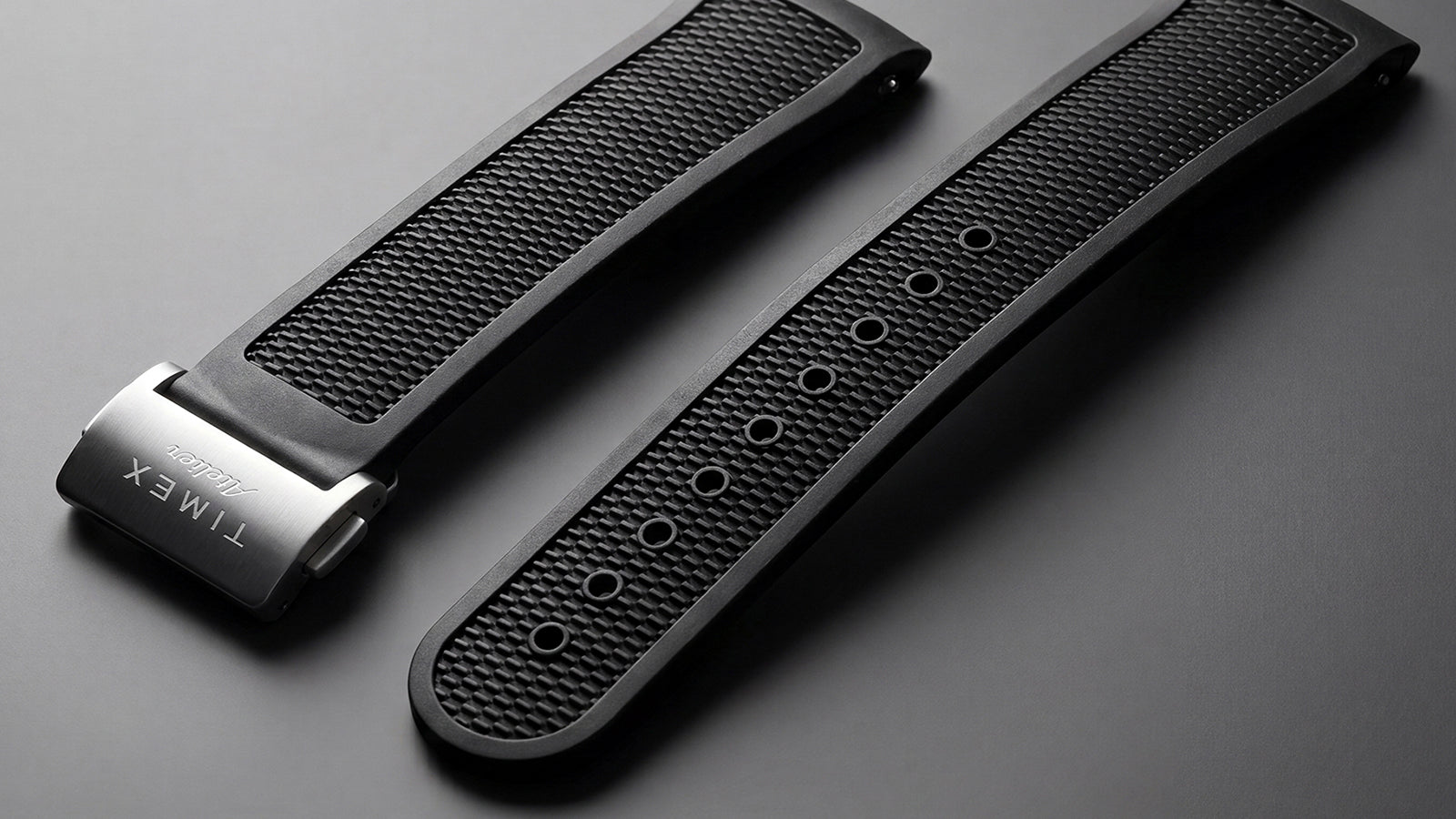 Timex Atelier black NBR synthetic rubber strap with textured panels, adjustment holes, and a brushed stainless-steel deployant clasp.