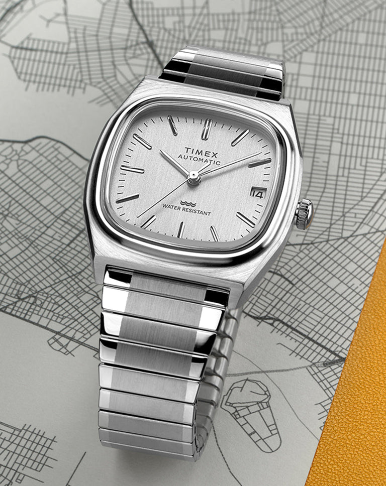 Timex E Line automatic watch with silver dial, cushion-shaped case, and stainless steel bracelet.