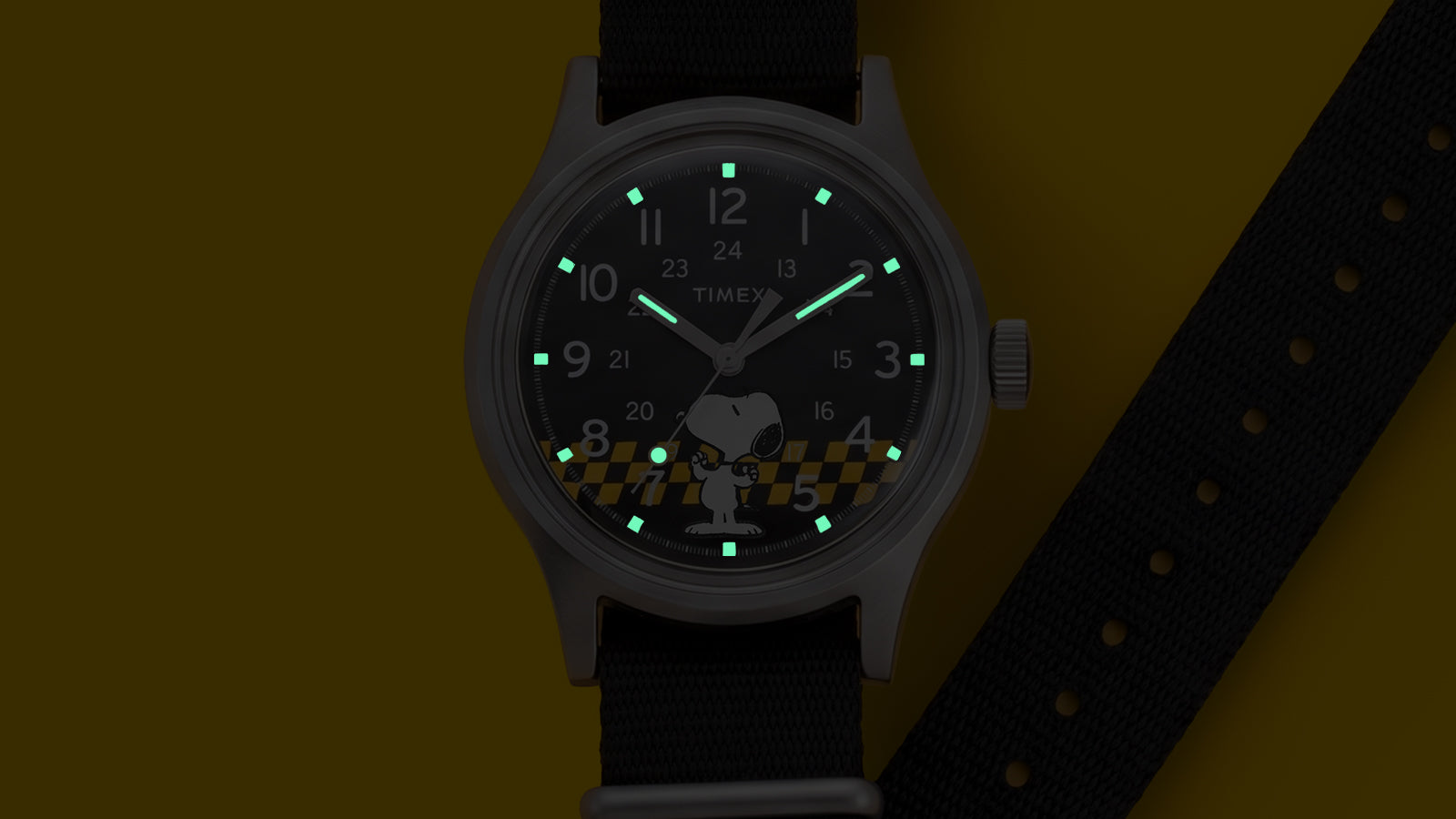 Peanuts® x Timex MK1® watch with INDIGLO® night-light illuminating the hands and hour markers, featuring Snoopy artwork on the black dial.