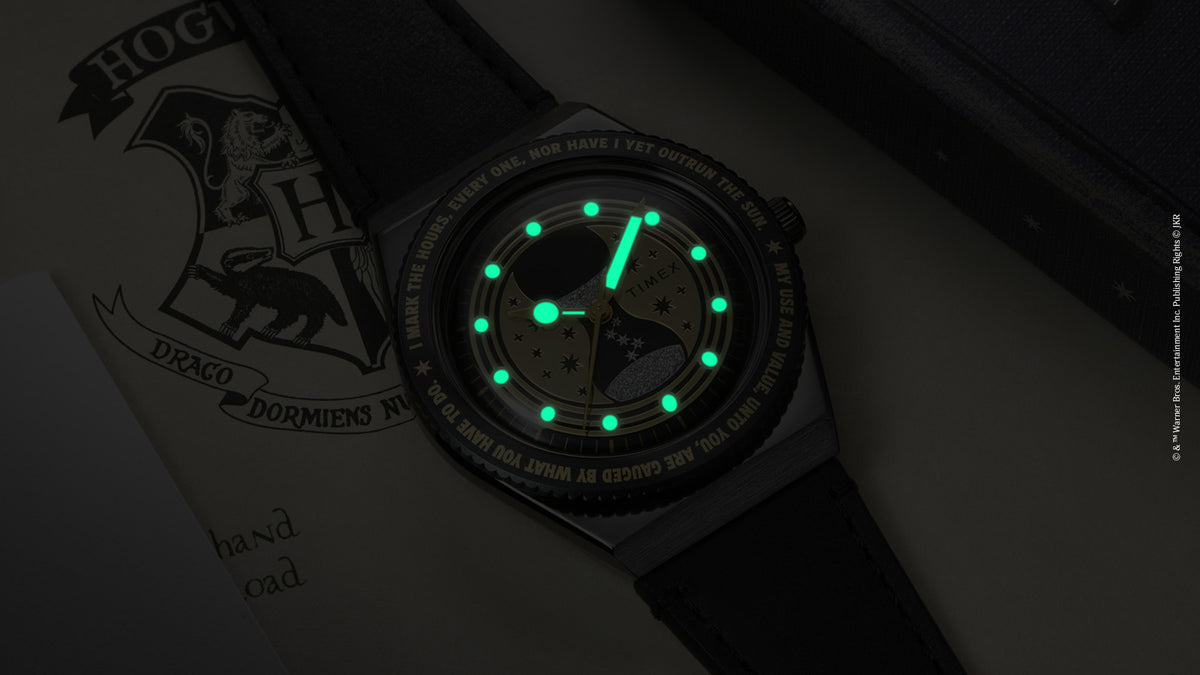 TW2Y76000 Close-up of the watch in low light, with green hands and hour markers glowing.