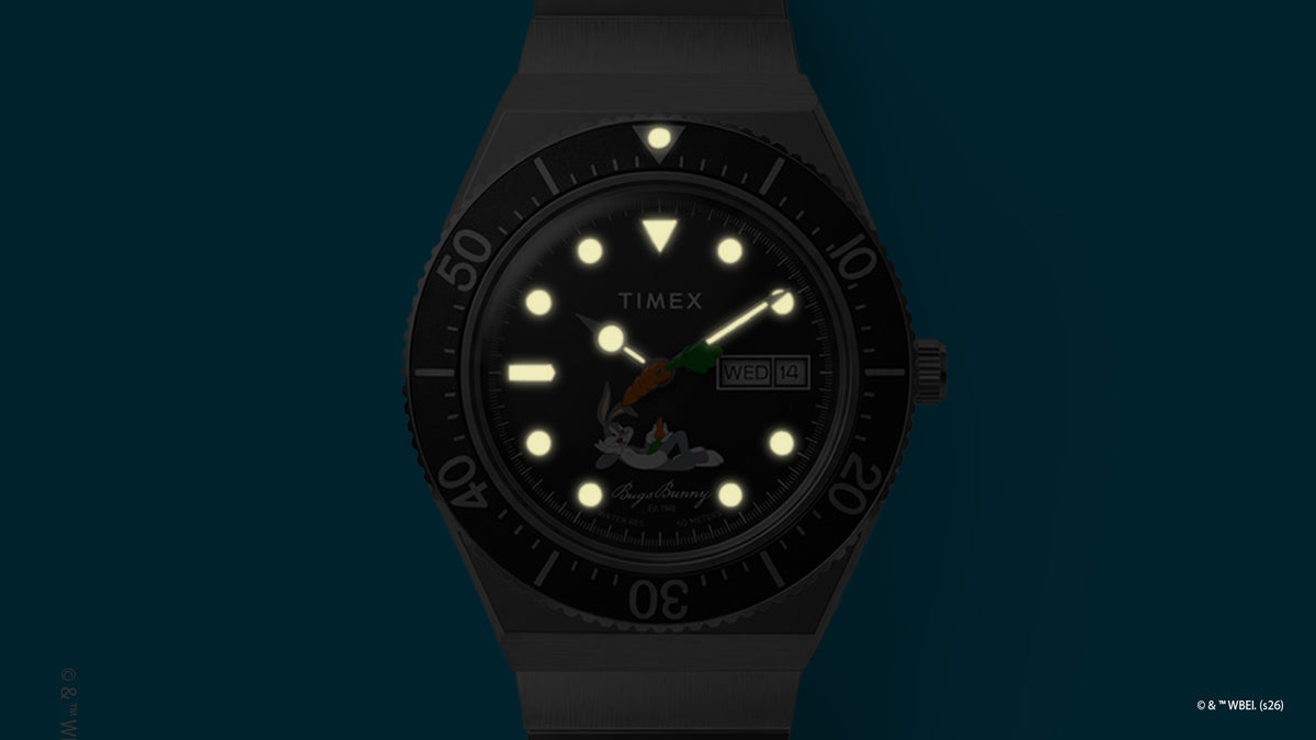 TW2Y99200 Bugs Bunny x Timex M79 watch with luminous hands, hour markers, and bezel marker glowing in the dark.
