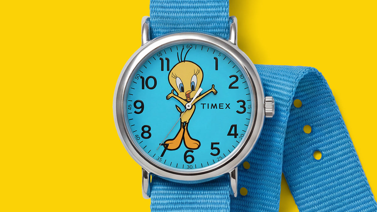 TW2Y99500 Front view of the Tweety Bird x Timex Weekender watch with a blue dial, silver-tone case, and matching blue fabric strap against yellow.