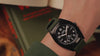 Timex Expedition® Capstone watch promotional video showcasing its rugged outdoor design. The video opens with close-up shots of the watch resting among dark textured rocks, emphasizing its brushed stainless-steel case, black dial, and olive green silicone strap.