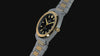 Timex Q Marbella two-tone stainless steel watch with a black textured dial, featuring rotating product views, close-up details of the gold-tone bezel and integrated bracelet, INDIGLO® illumination, and wrist shots highlighting its modern design.