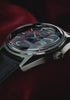 Video showcasing the Q Timex® Red Vega 1978 Reissue watch, highlighting the red and black patterned dial, day-date window, stainless steel case, domed crystal, and black leather strap.