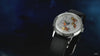 A promotional video showcasing the Timex x Peanuts® Marlin® Automatic Space watch. The watch features a silver dial illustrated with Snoopy, Charlie Brown, Lucy, Franklin, and Peppermint Patty in orange space suits floating inside a spacecraft. The animation transitions between close-up shots of the dial, the automatic movement visible through the transparent caseback decorated with Peanuts characters, and lifestyle shots of the watch being worn.